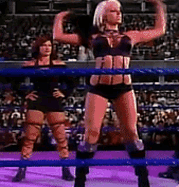 two women are standing in a wrestling ring and one is flexing her arms