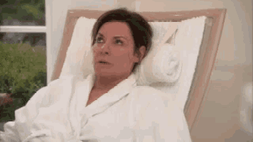 a woman in a robe is laying in a chair with towels on her head .