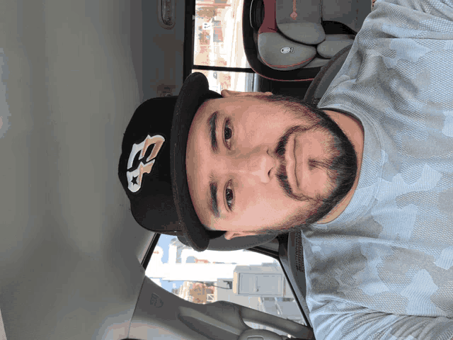 a man wearing a hat with the letter b on it is sitting in a car