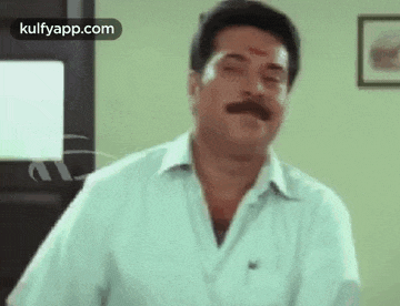 a man with a mustache is making a funny face while standing in front of a door .