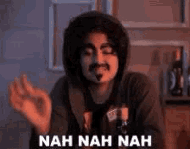 a man in a hooded jacket is making a funny face and saying `` nah nah nah '' .