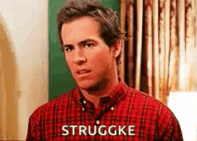 a man in a plaid shirt is standing in front of a window with the words strugge written on his shirt .
