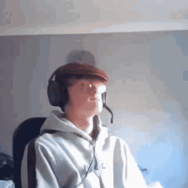 a young man wearing headphones and a flat cap is sitting in a chair .
