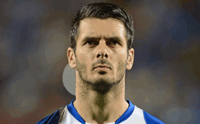a man with a beard wears a blue and white shirt