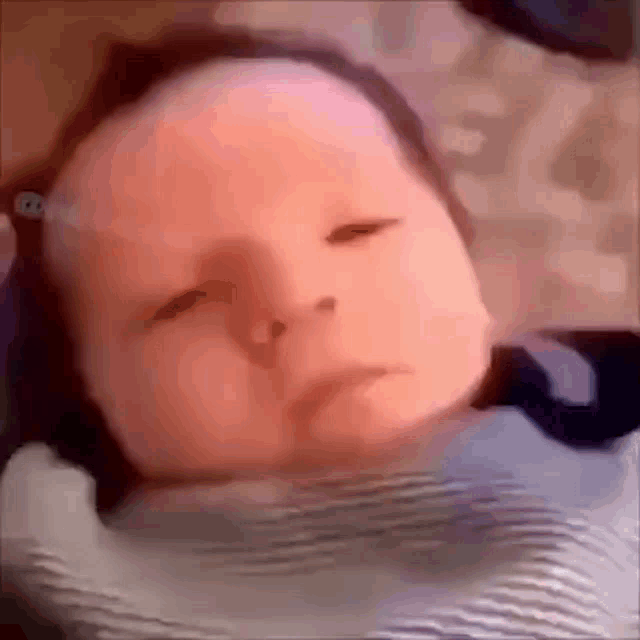 a close up of a baby 's face with a sad look on its face .