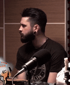 a man with a beard is sitting in front of a microphone wearing a t-shirt that says iowa