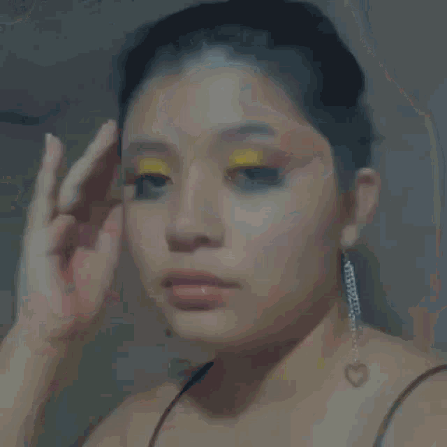 a close up of a woman 's face with yellow eye shadow and black eyeshadow .