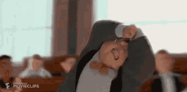 a man in a suit is laying on his back in a courtroom with his hands on his head .