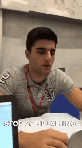 a man sitting at a desk with the words stop complaining written below him