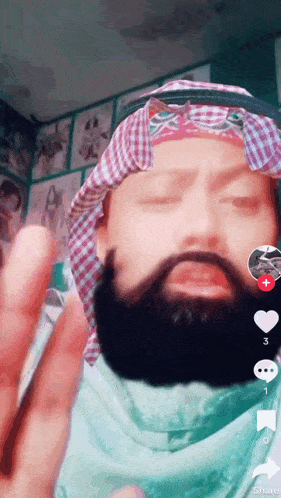 a man with a beard is wearing a head scarf and sunglasses