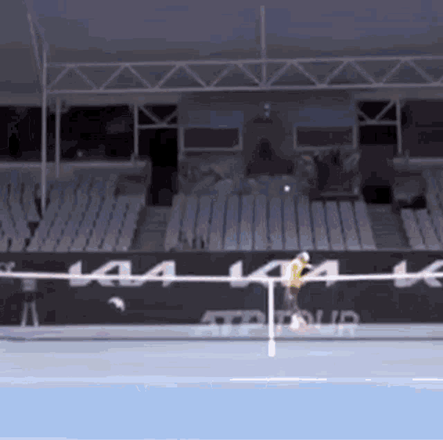 a tennis player is hitting a tennis ball on a court with a kia banner in the background