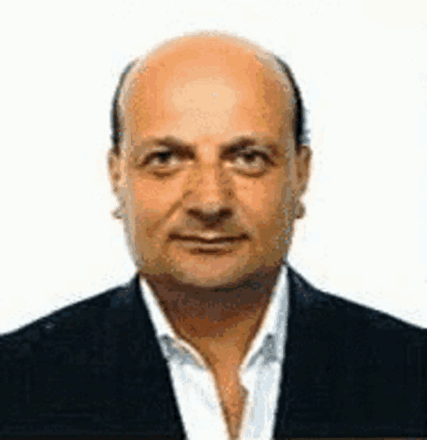 a bald man in a suit and white shirt is looking at the camera .