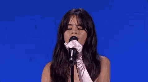 a woman in white gloves is singing into a microphone on a stage .