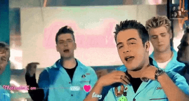 a group of young men in blue overalls are dancing in front of a sign that says " long "