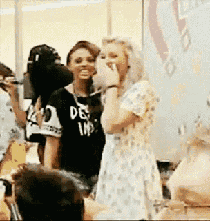 a group of women are standing next to each other in a room and one of them is laughing .