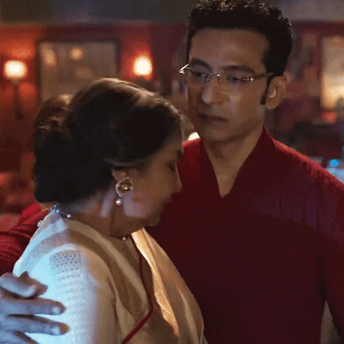 a man in a red shirt is hugging a woman