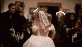 a bride is dancing in front of a crowd of people at a wedding .