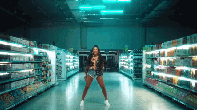 a woman is dancing in a grocery store aisle that has a sign that says ' coca cola ' on it