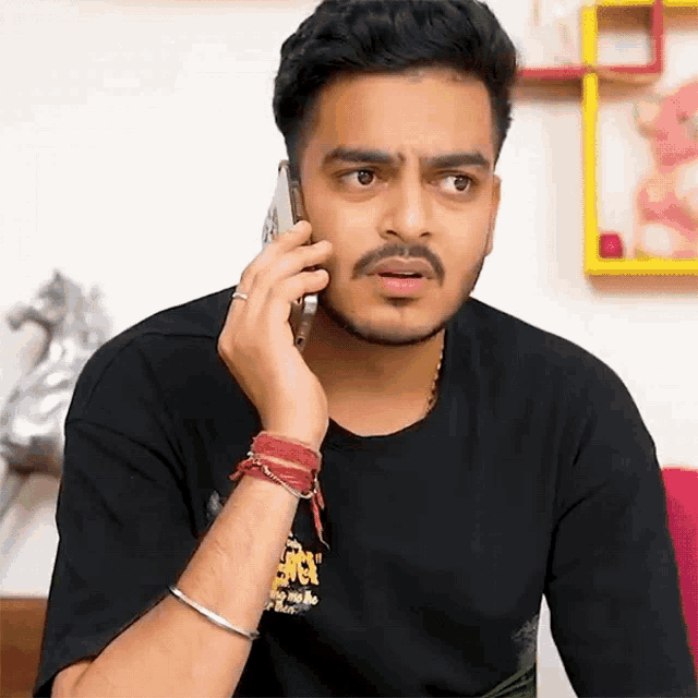 a man wearing a black shirt is talking on a cell phone .