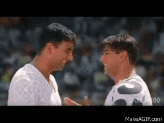 two men are standing next to each other and looking at each other in front of a crowd .