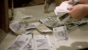a person is counting a stack of 100 bills on a table