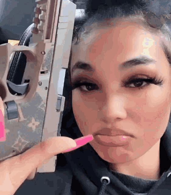 a woman is holding a gun in her hand and making a face .