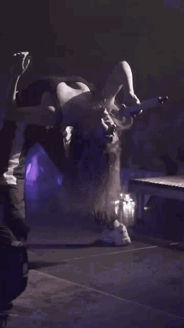a woman upside down on a stage with a microphone