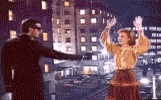 a man and a woman are dancing in a city at night .