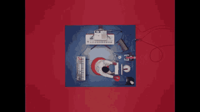 an aerial view of a man playing a keyboard on a red background