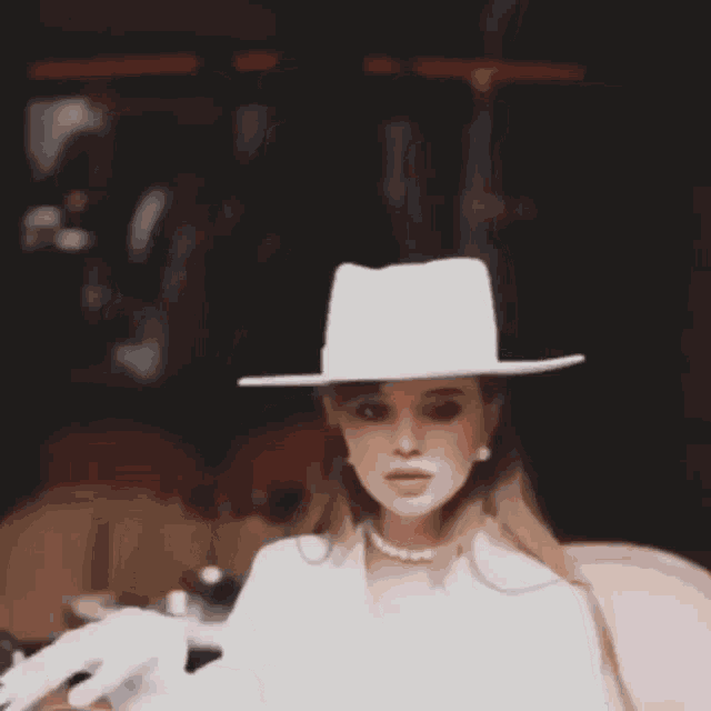 a woman wearing a white hat and a pearl necklace is sitting in a chair .
