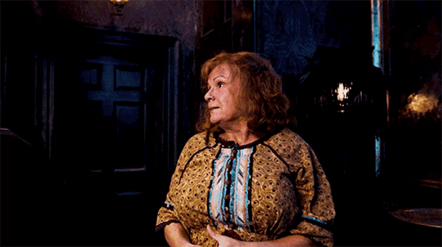 a woman standing in a dark room with a lantern on the wall