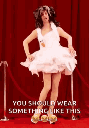 a man in a white dress is standing on a red carpet and laughing .
