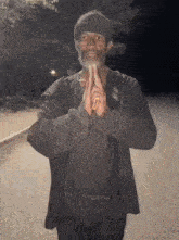 a man with a beard is praying with his hands folded .