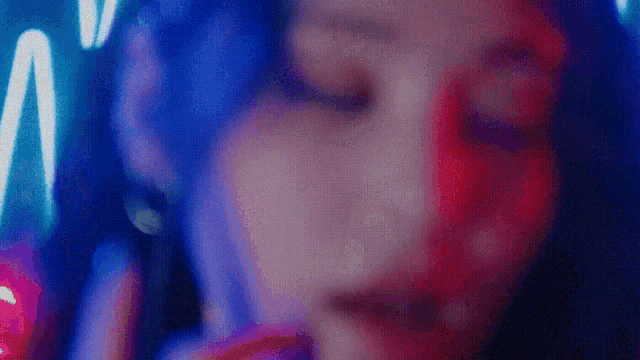 a close up of a woman 's face with blue and red lights behind her