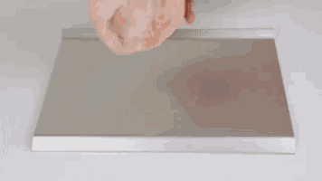 a person is holding a piece of meat on top of a metal tray .