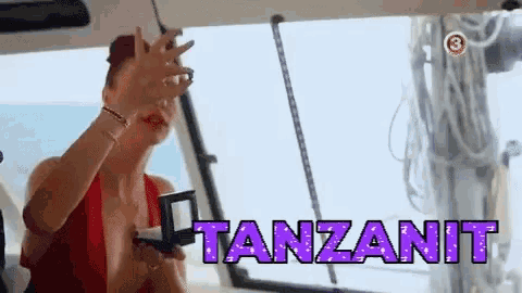 a woman in a red dress is sitting on a boat with the word tanzanit written on the screen