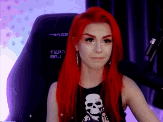 a woman with red hair is sitting in a gaming chair .