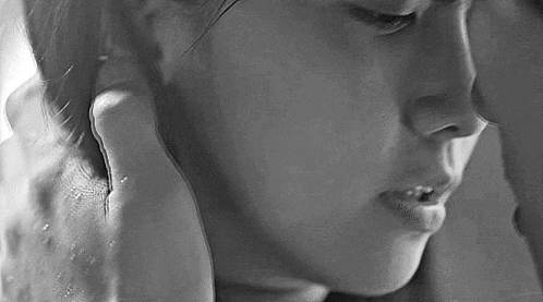 a black and white photo of a woman 's face with a hand on her ear .