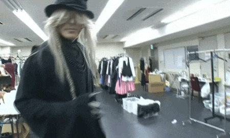 a man in a costume is standing in a room with clothes hanging on the racks .