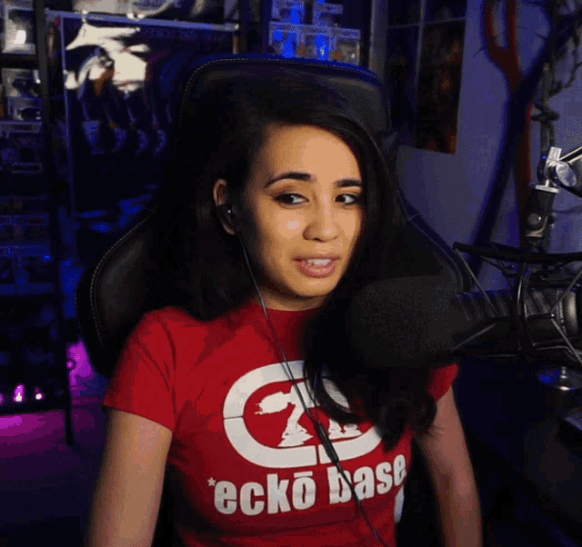 a woman wearing a red ecko base t-shirt sitting in front of a microphone