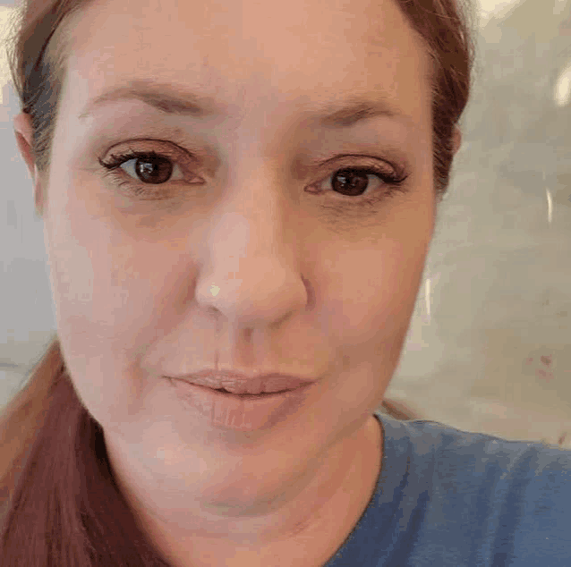 a close up of a woman 's face with a ponytail and a nose ring .