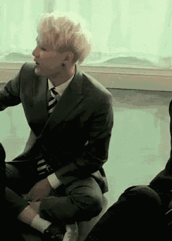 a man in a suit and tie is sitting on the floor in a room .