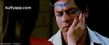 a man with a woman 's hand on his face has a stitch on his forehead .