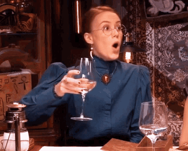 a woman is holding a glass of wine in front of a box that says e on it
