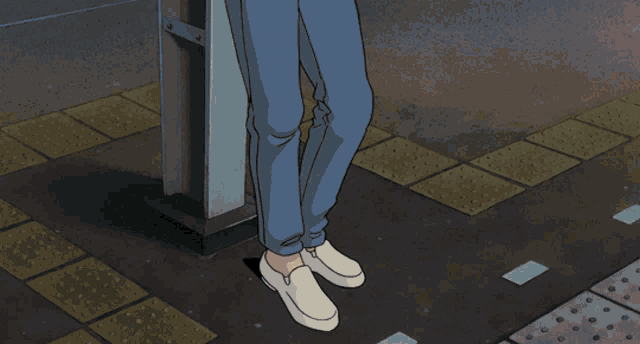 a person wearing white shoes is standing on a sidewalk next to a pole