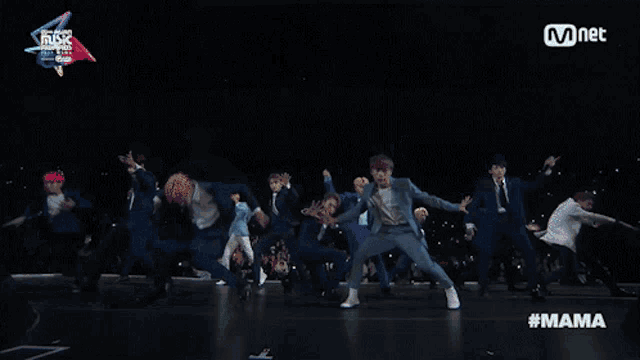 a group of men are dancing on a stage with mnet in the corner