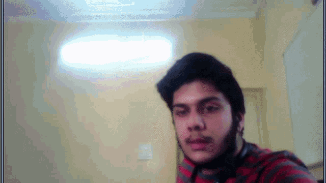 a man with a beard is taking a selfie in front of a yellow wall
