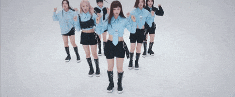 a group of women in blue shirts are dancing together in a room .