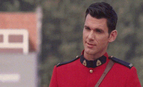 a man in a red uniform is standing in front of a building and looking at the camera .