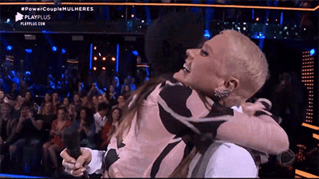 a man is holding a woman in his arms in front of a crowd and the words power couple mulheres are on the screen